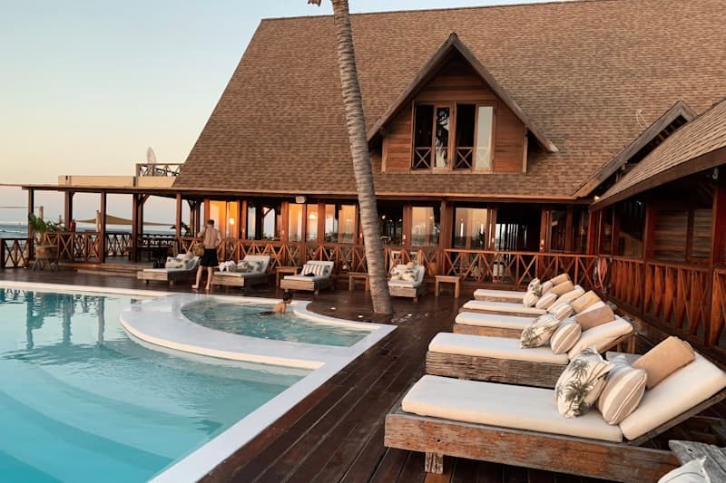 Resort pool deck at twilight with palm trees and calm water